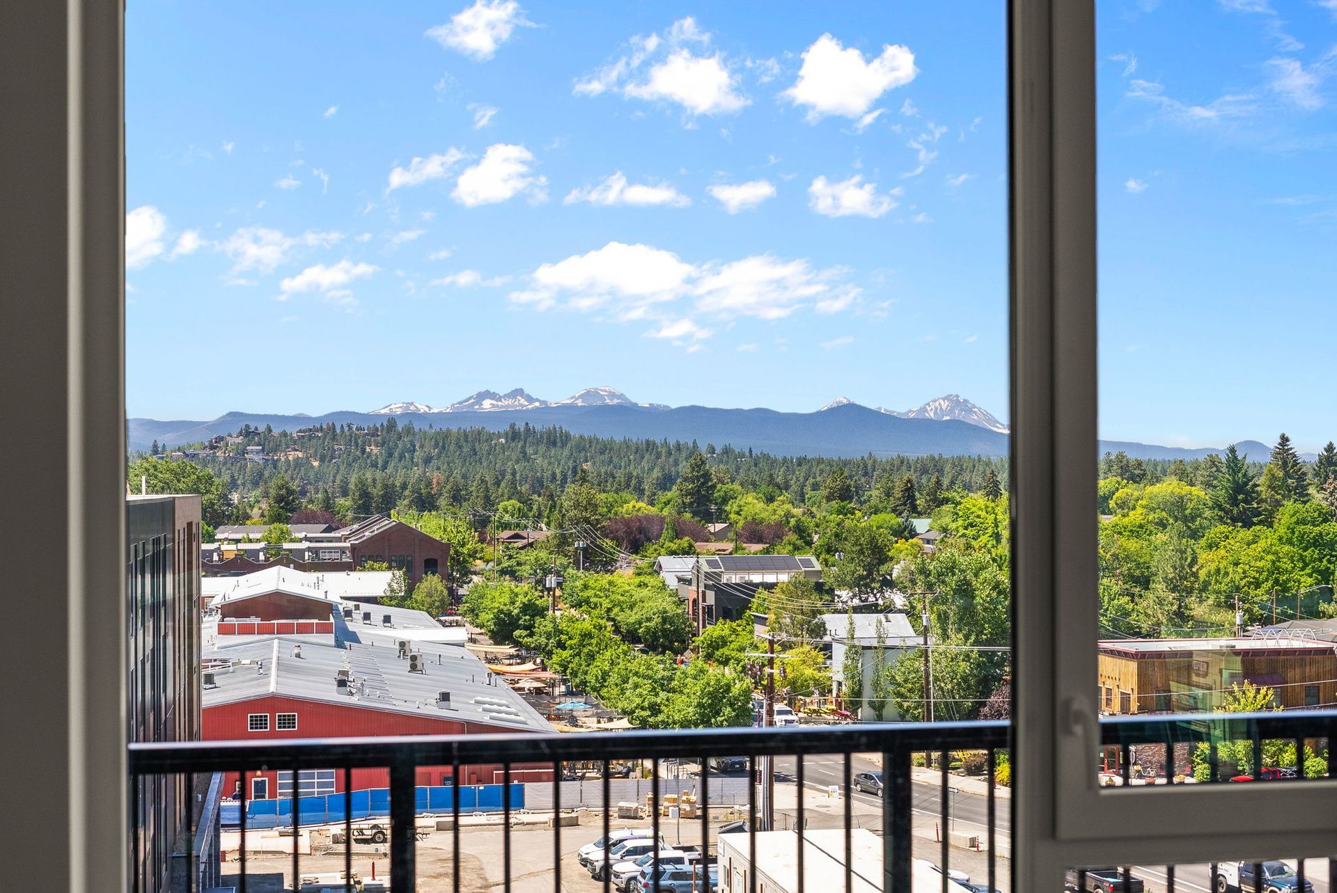 View from a balcony overlooking a town and mountains on a sunny day.