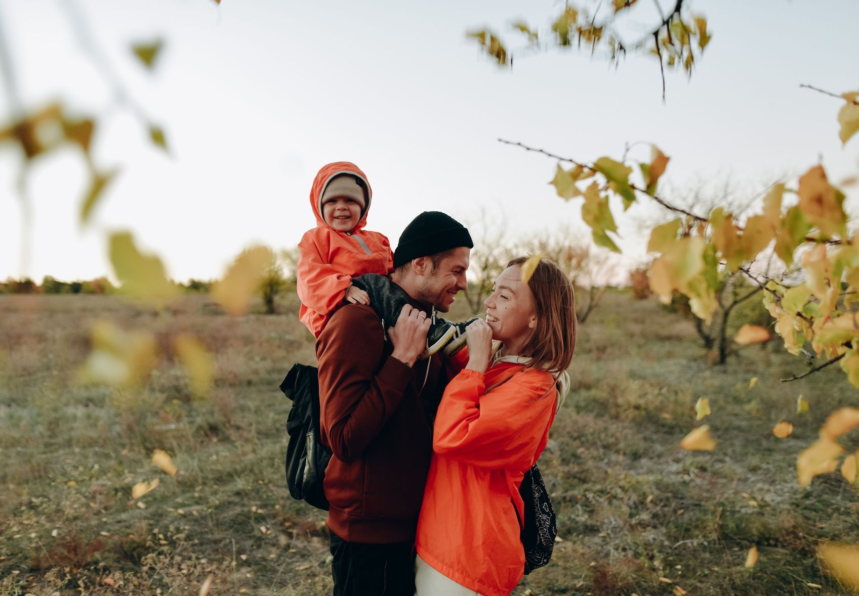 A man is carrying a child on his shoulders in a field.