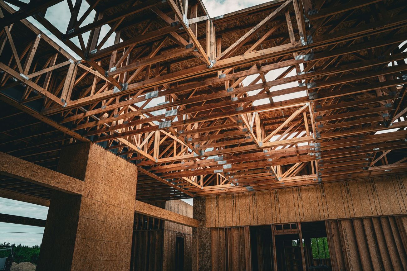 Partially built interior with exposed wooden roof trusses and brick walls under construction