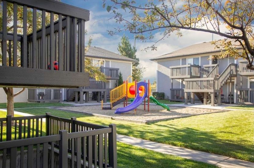 there is a playground in the middle of a lush green park .