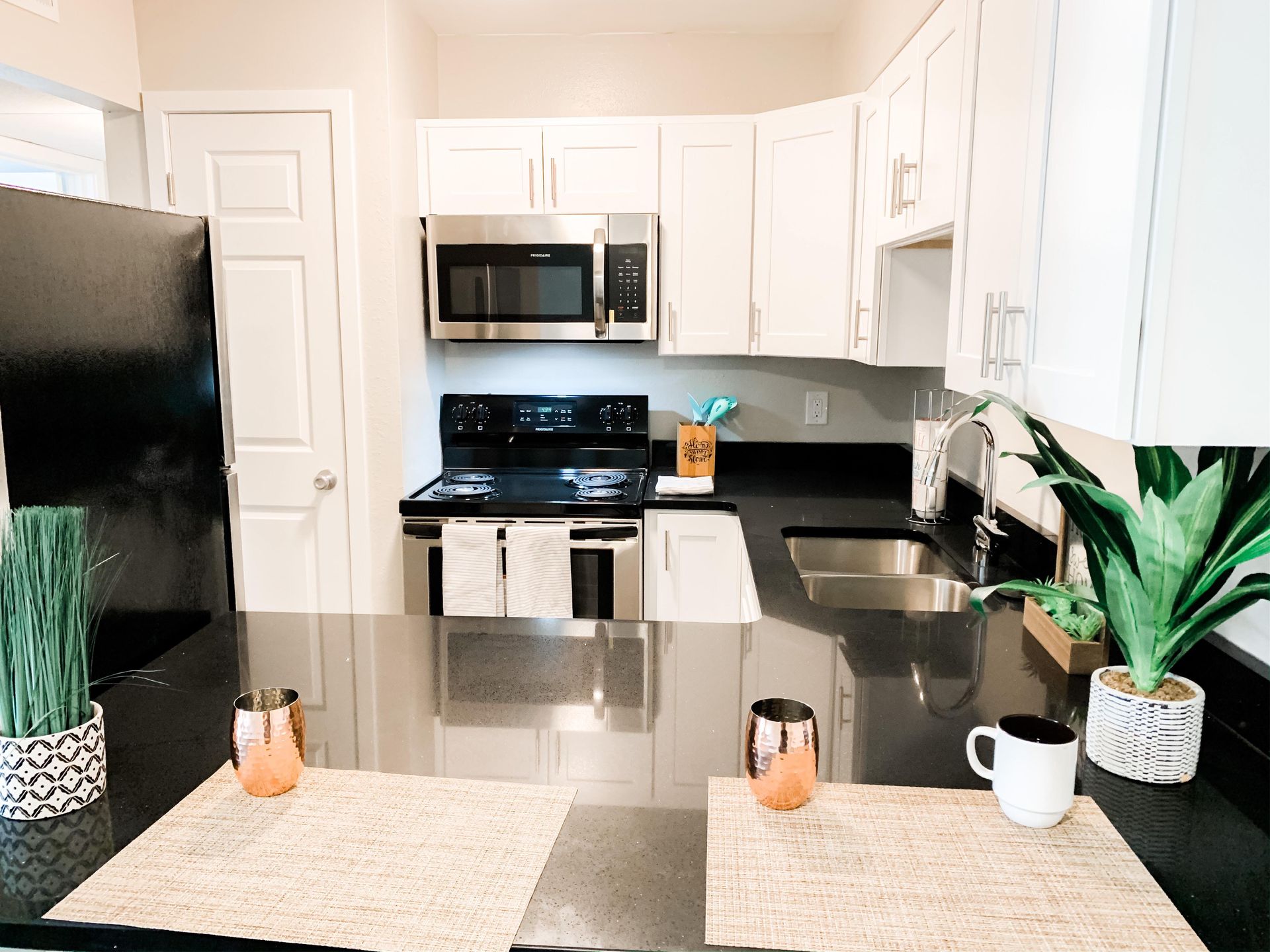 a kitchen with white cabinets , stainless steel appliances , a sink , and a microwave .