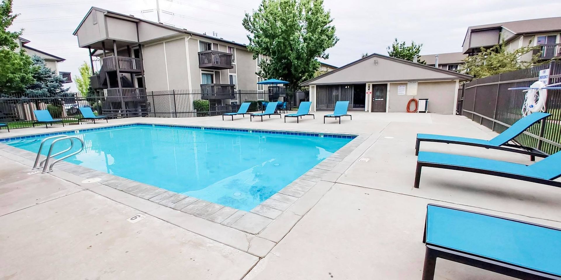 a large swimming pool surrounded by blue lounge chairs in front of a building .
