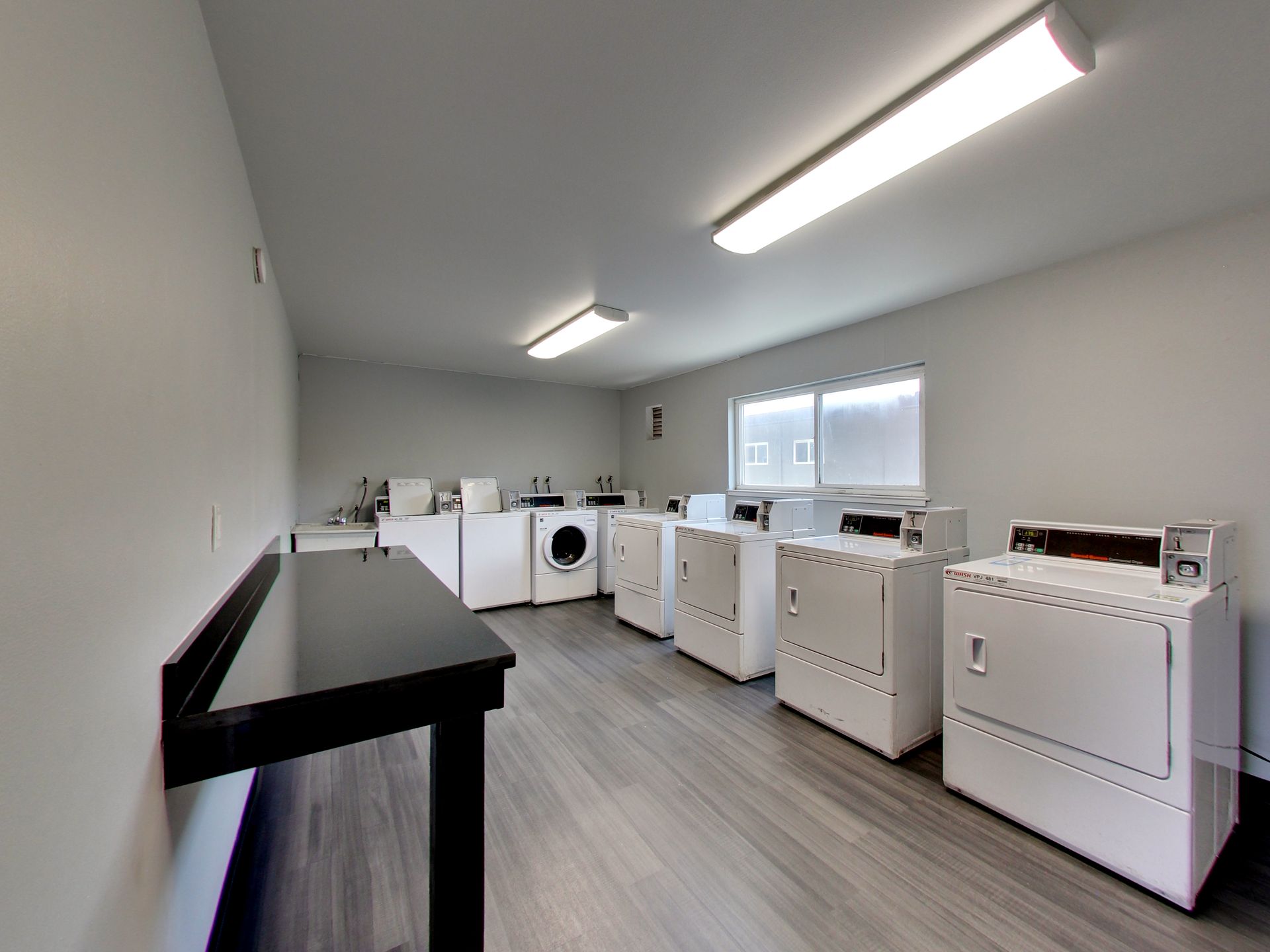 a laundry room with a row of washing machines and dryers .