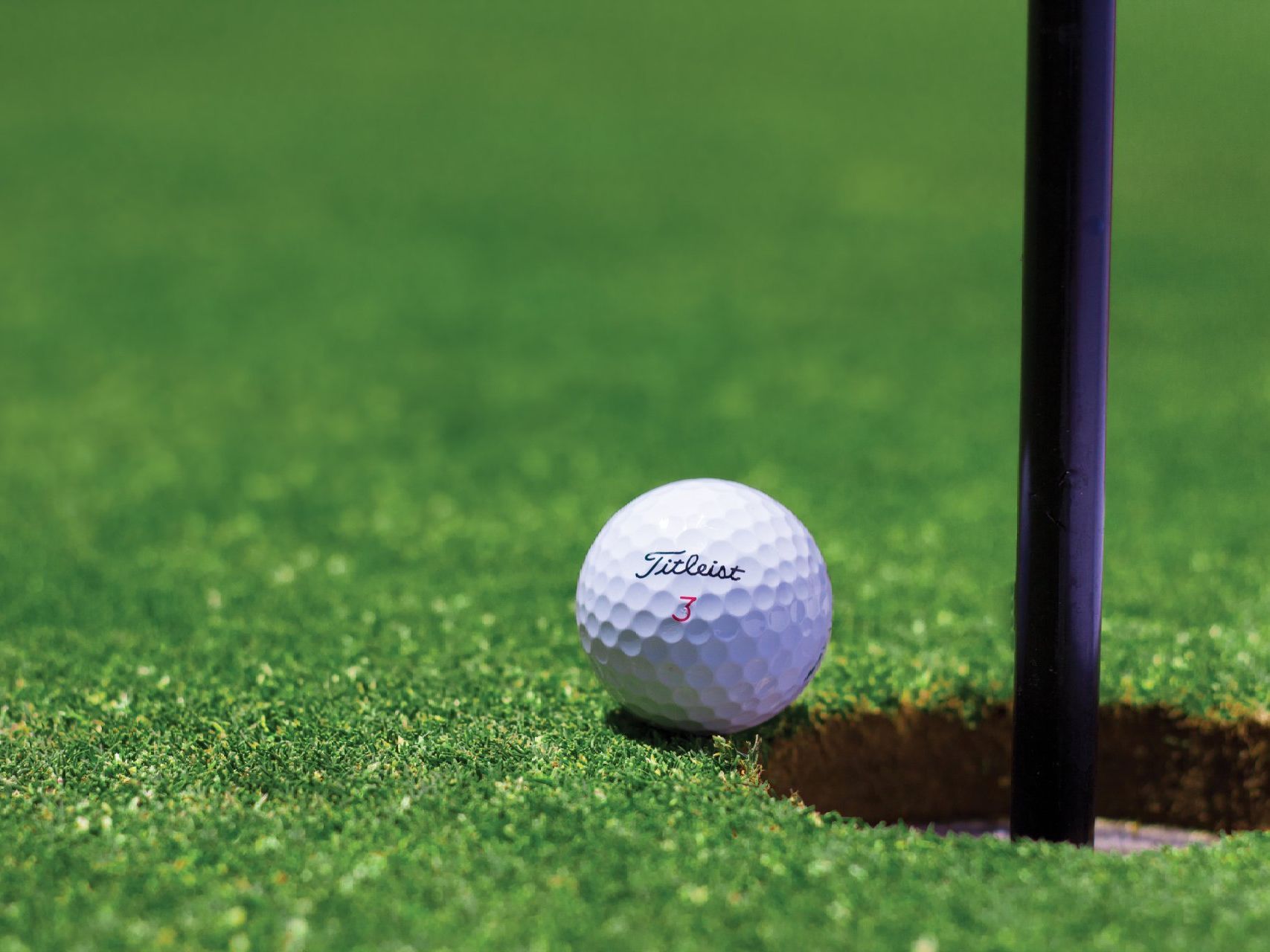 a golf ball is sitting on top of a green next to a hole .