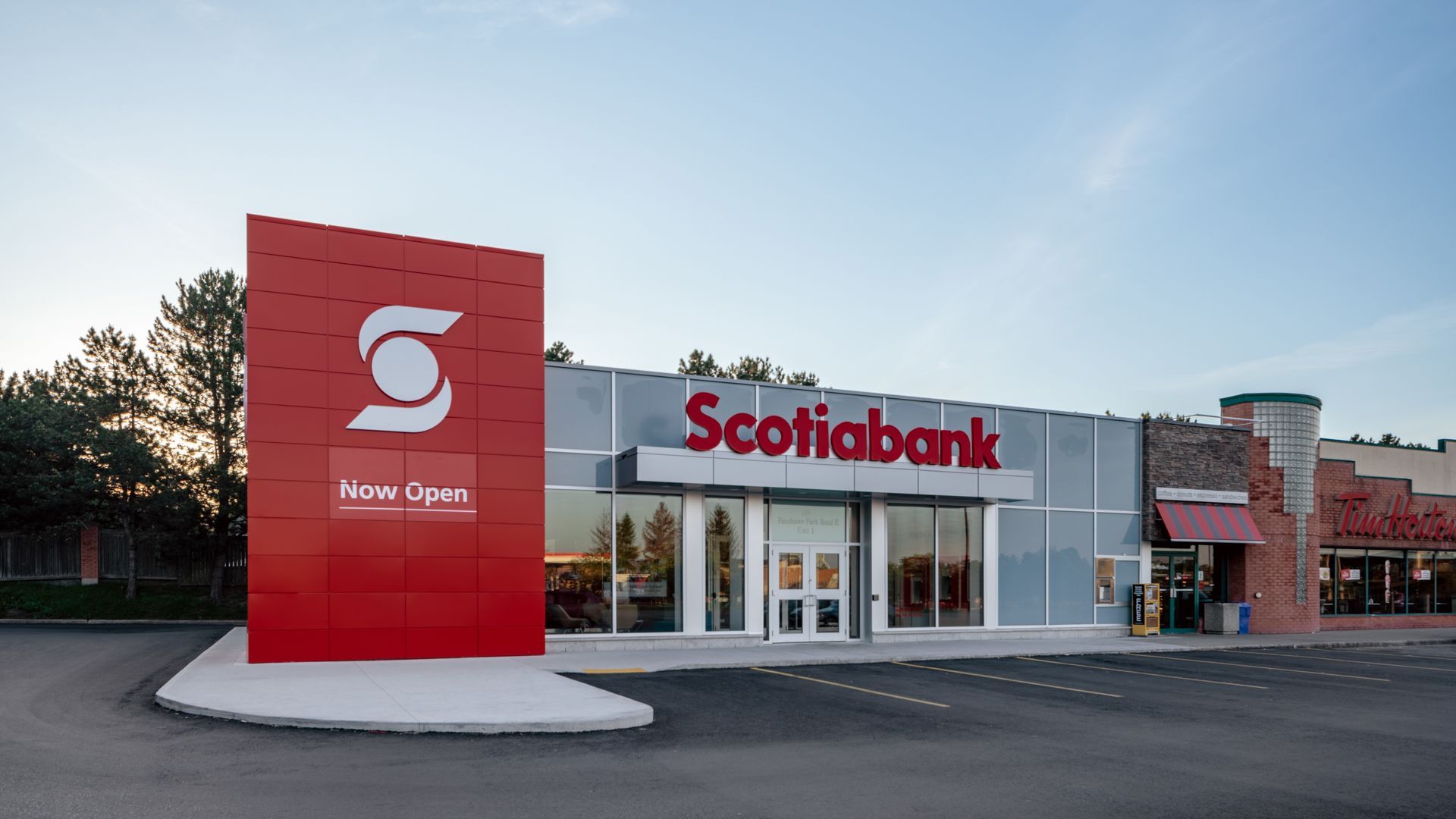 Scotiabank branch with a red sign, glass front, and parking lot in front.