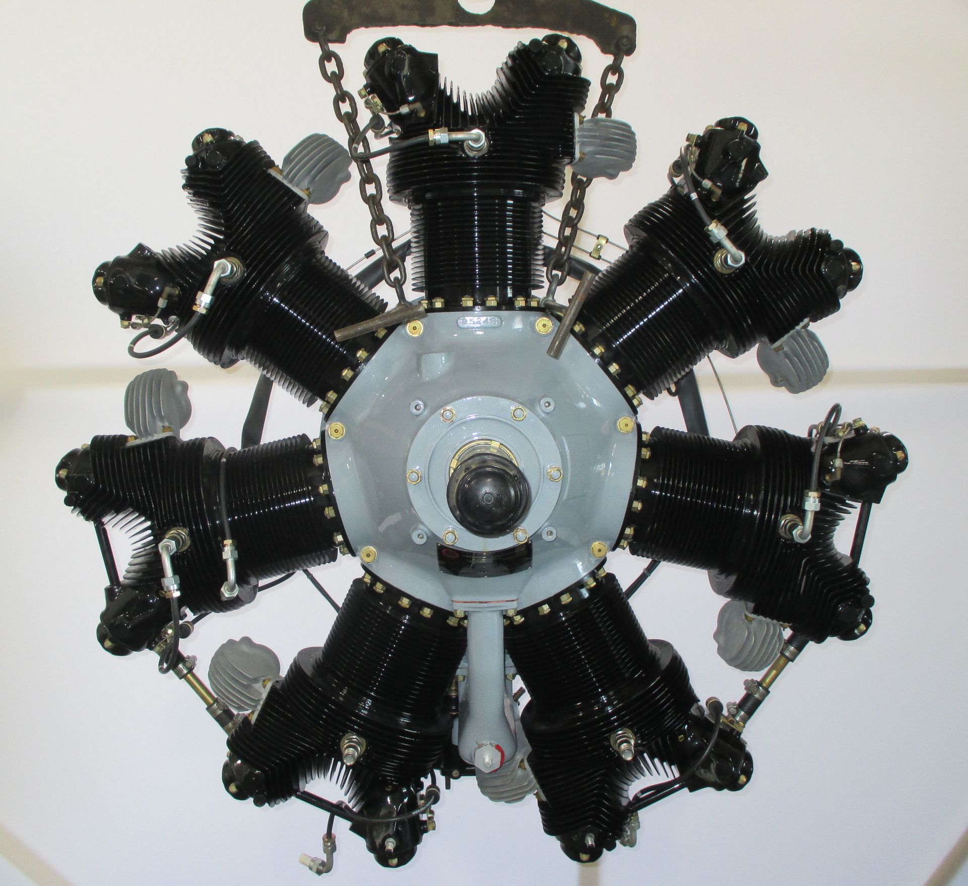 Radial aircraft engine with black cylinders, hanging from chains.
