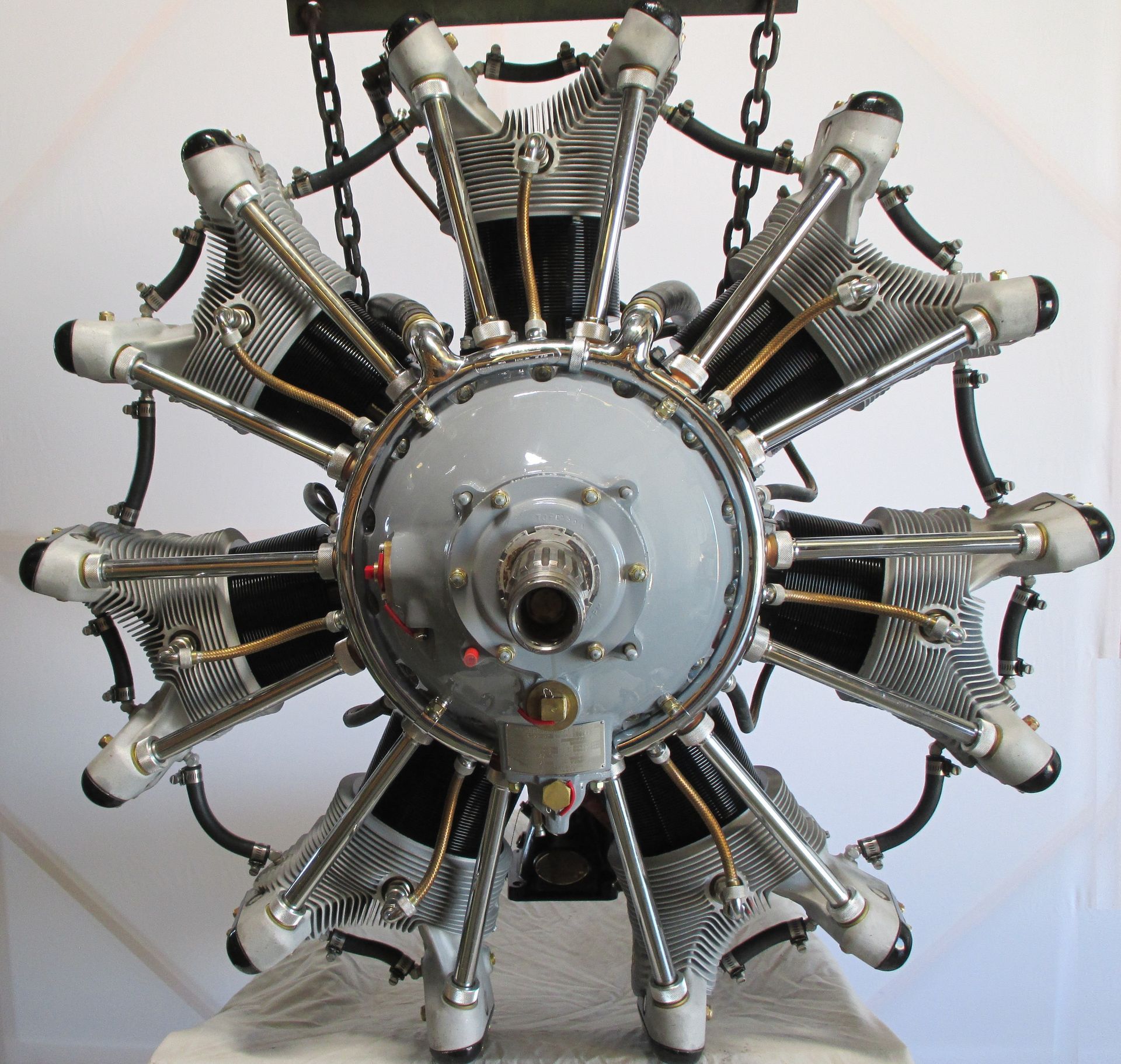 Radial aircraft engine, metal construction, suspended by chains. Cylinder heads and crankcase are visible.