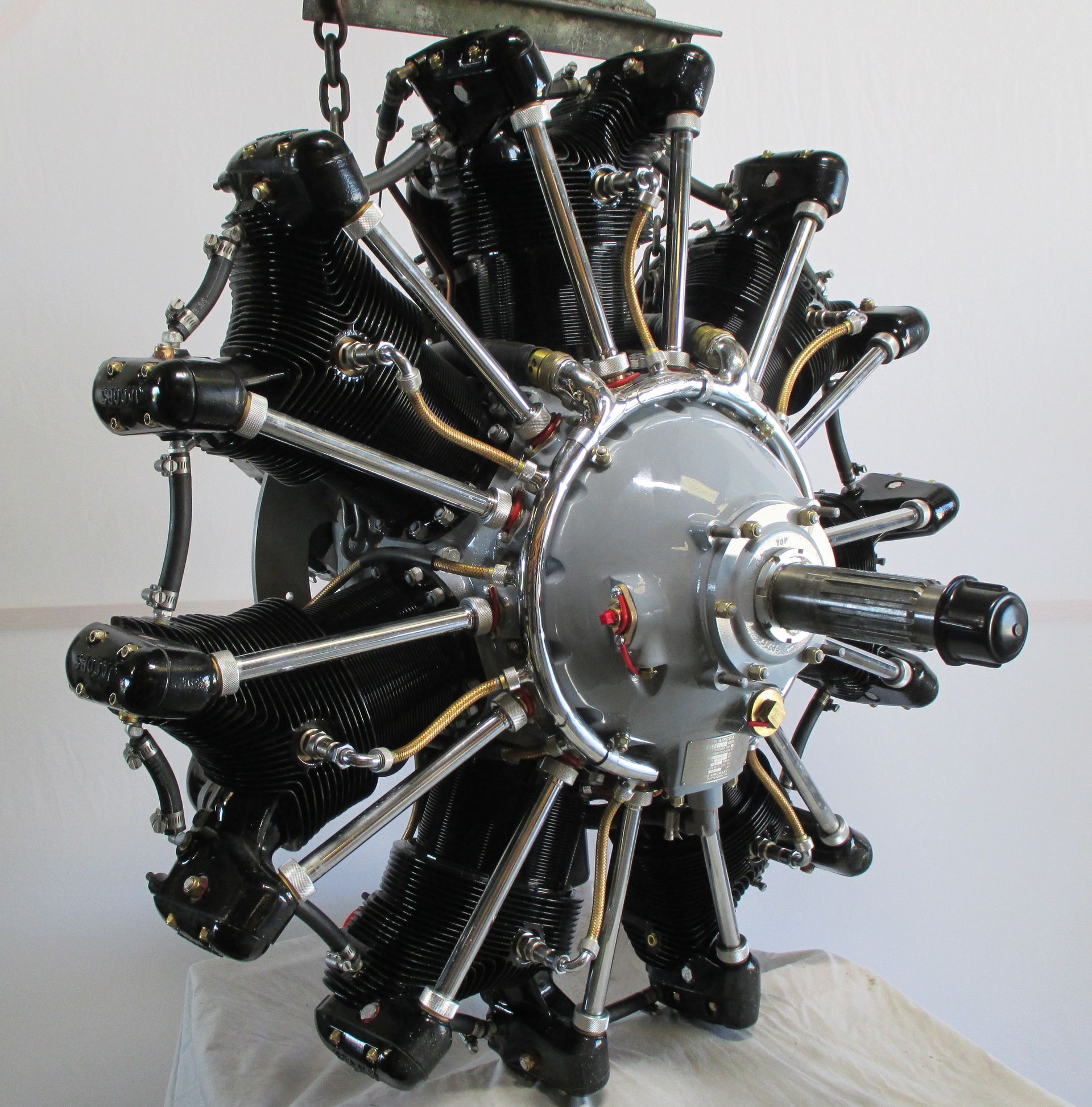 Radial aircraft engine, dark cylinders, silver casing, yellow fuel lines.