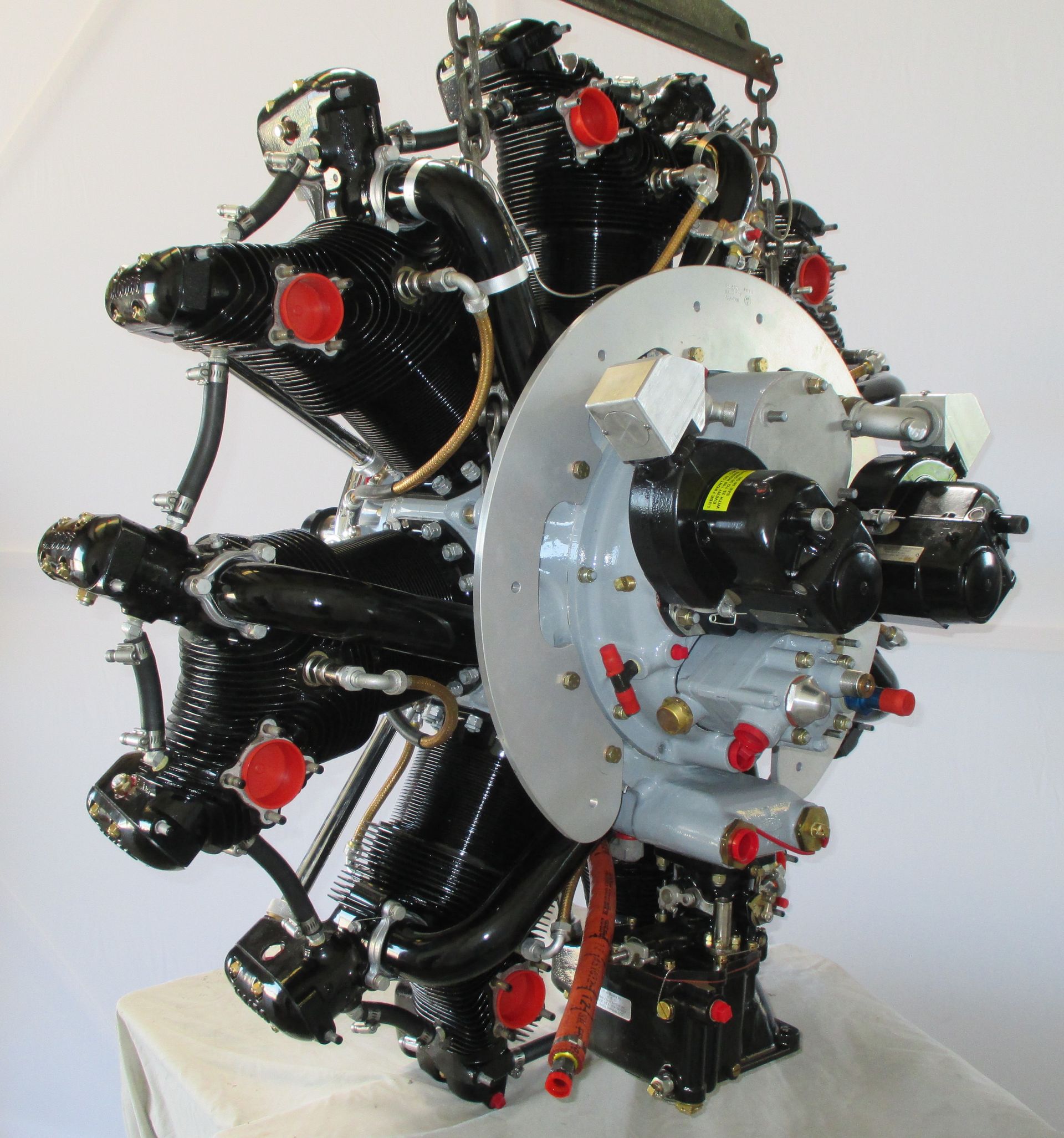 Radial aircraft engine, black and silver, with red caps, hanging.