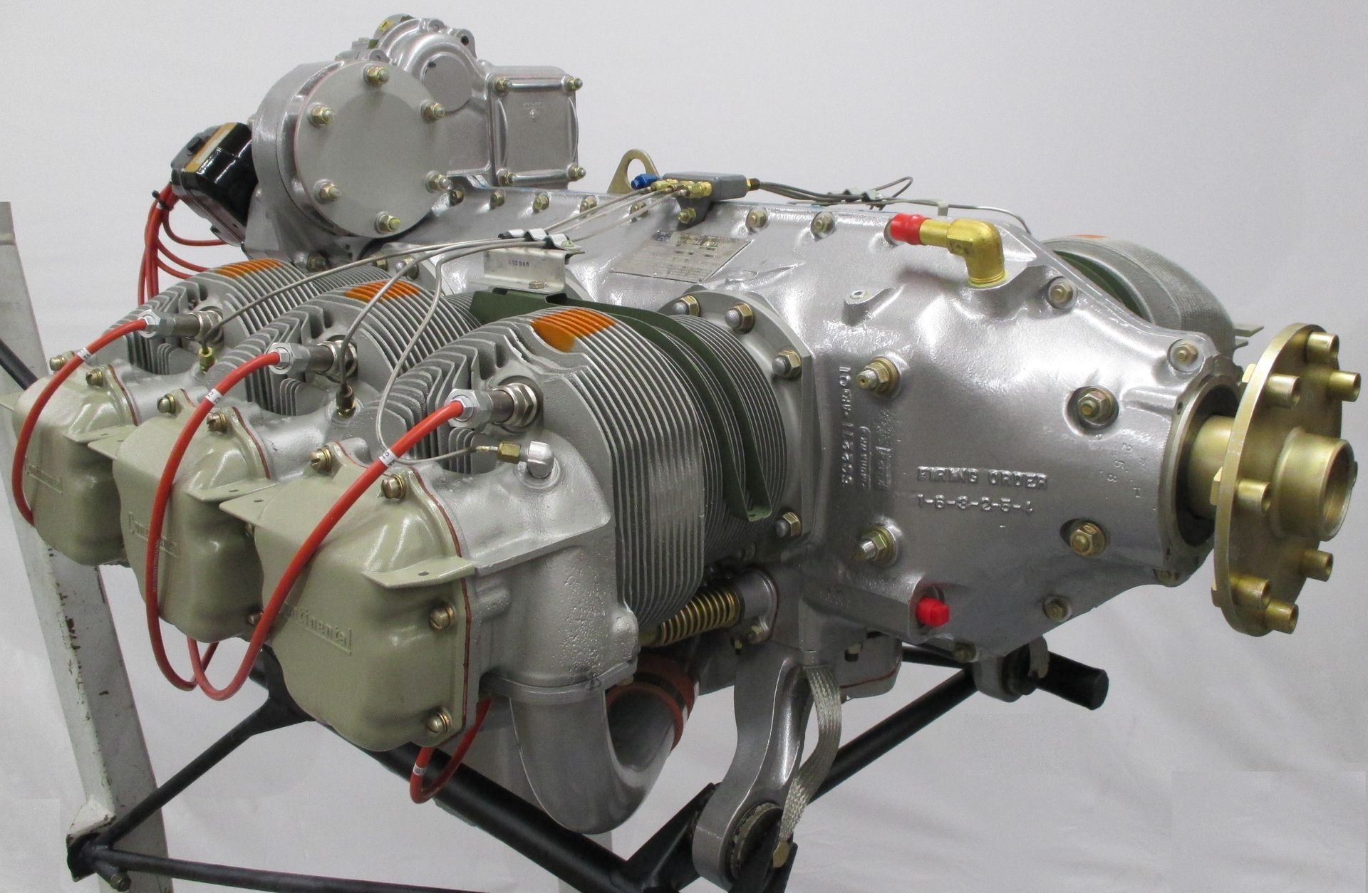 Aircraft engine, silver metal, four cylinders, mounted on a stand.