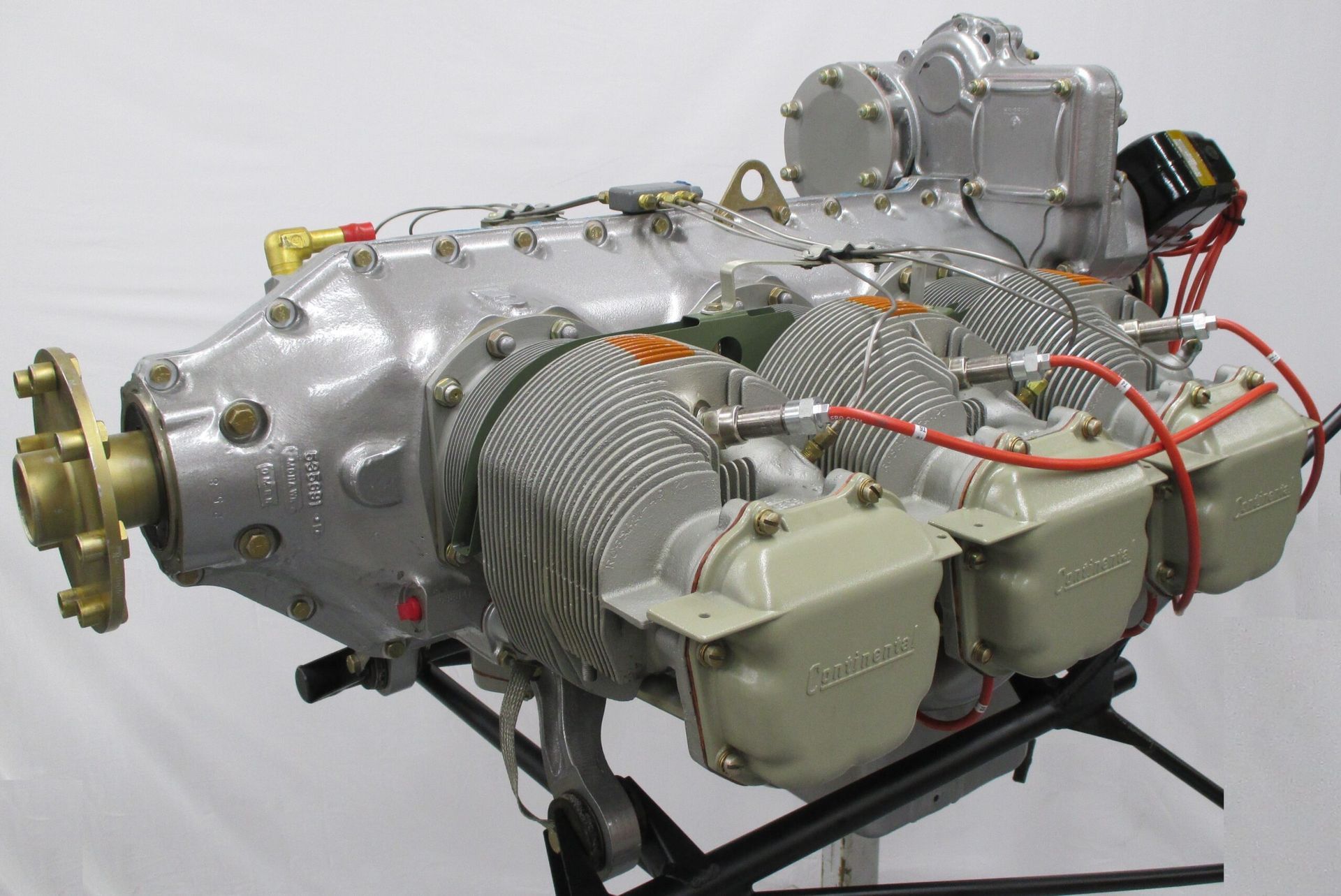Aircraft engine, aluminum finish, cylinders visible, mounted on stand.