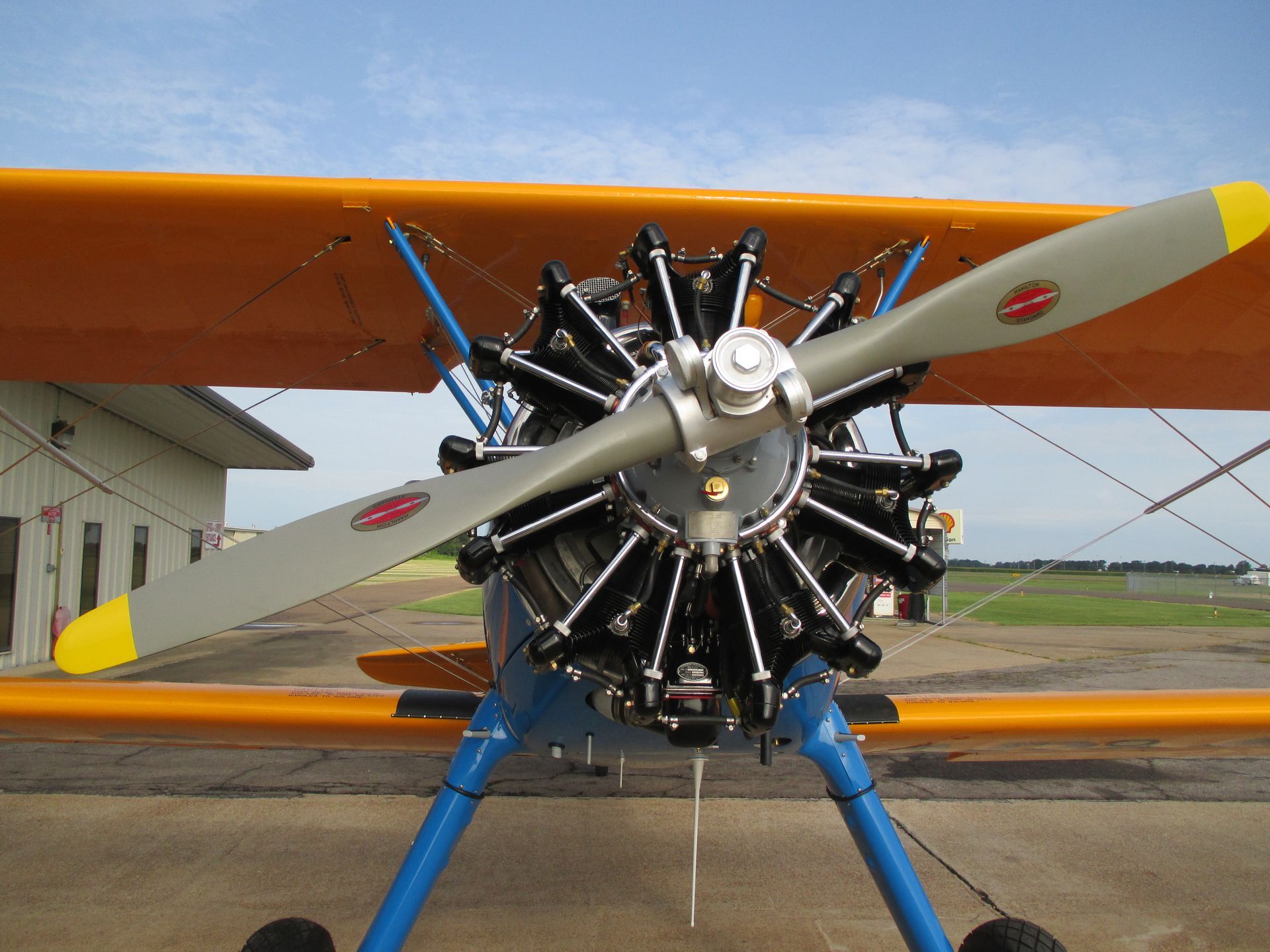Biplane with radial engine, yellow wings, blue struts, and a gray propeller.