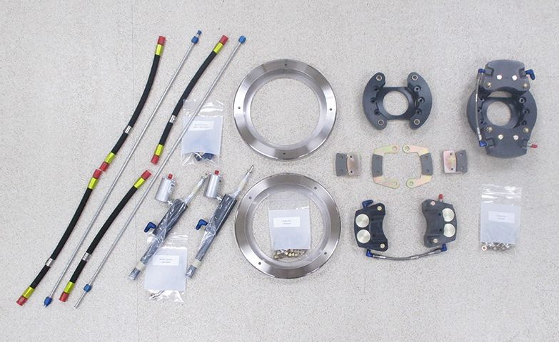 An assortment of aircraft brake parts, including lines, calipers, and rotors, spread out for assembly.