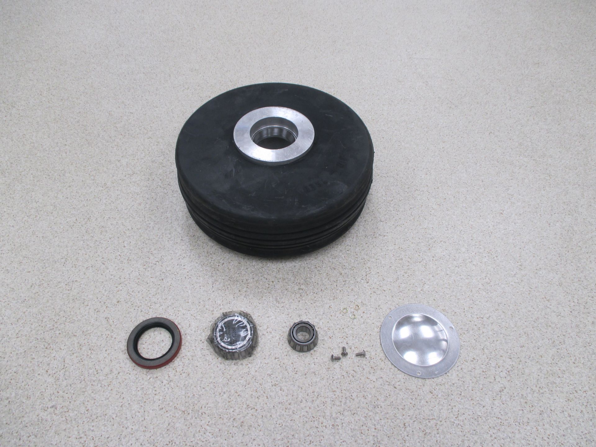 Black rubber wheel and disassembled components on a neutral surface.