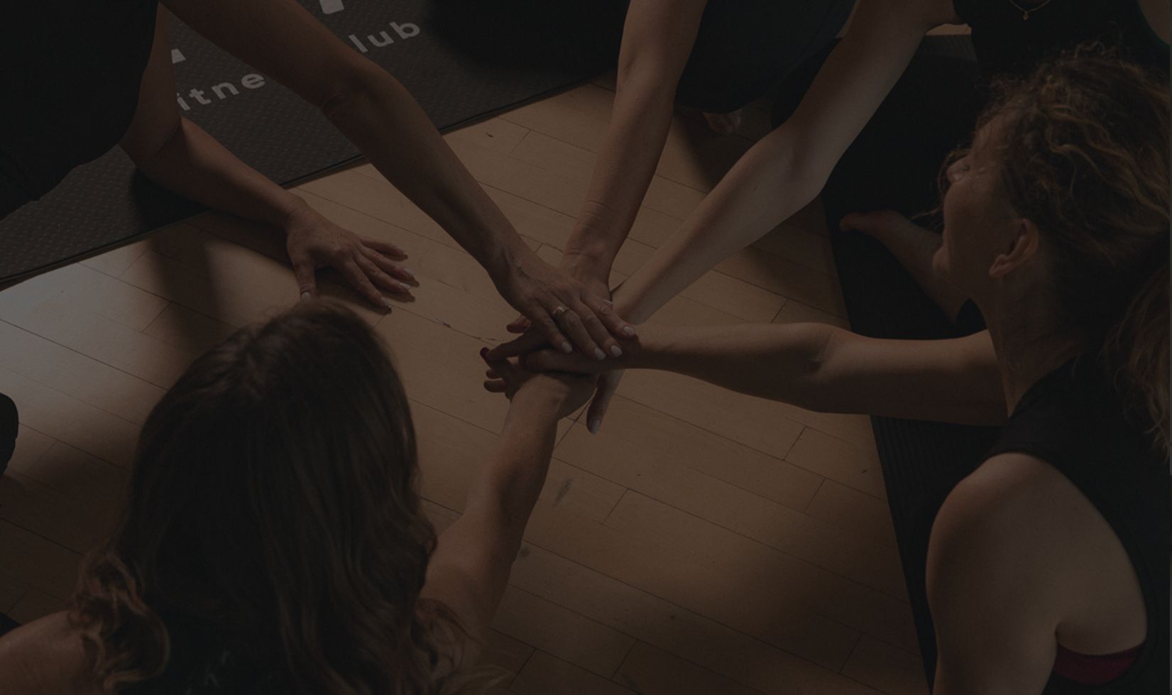 Klientki klubu fitness w Warszawie łączą dłonie po treningu – promocja 50% na kolejny miesiąc