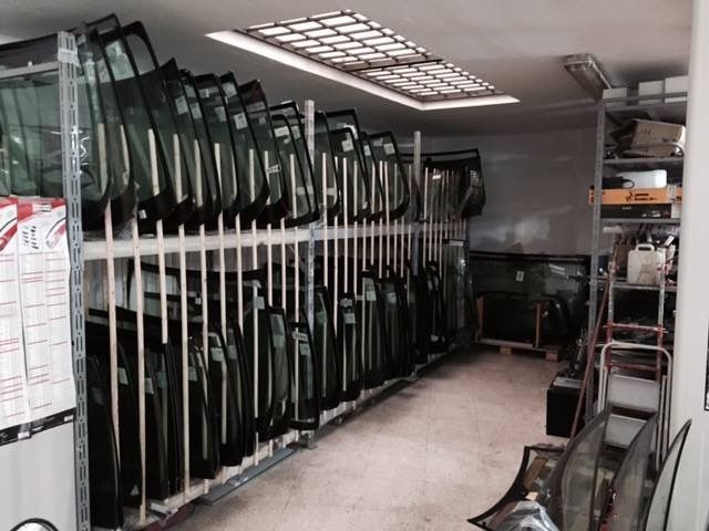 File di portiere d'auto verdi, immagazzinate in posizione verticale in un'officina o in un magazzino di vetri per auto.