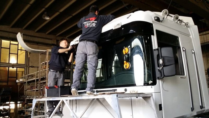 Due operai sono in piedi su una piattaforma e stanno installando dei componenti sulla cabina 