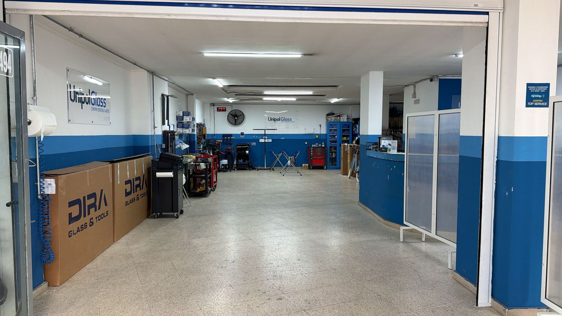 Interno vuoto di un'officina meccanica con pareti blu e bianche, biciclette parcheggiate e un ampio spazio aperto.