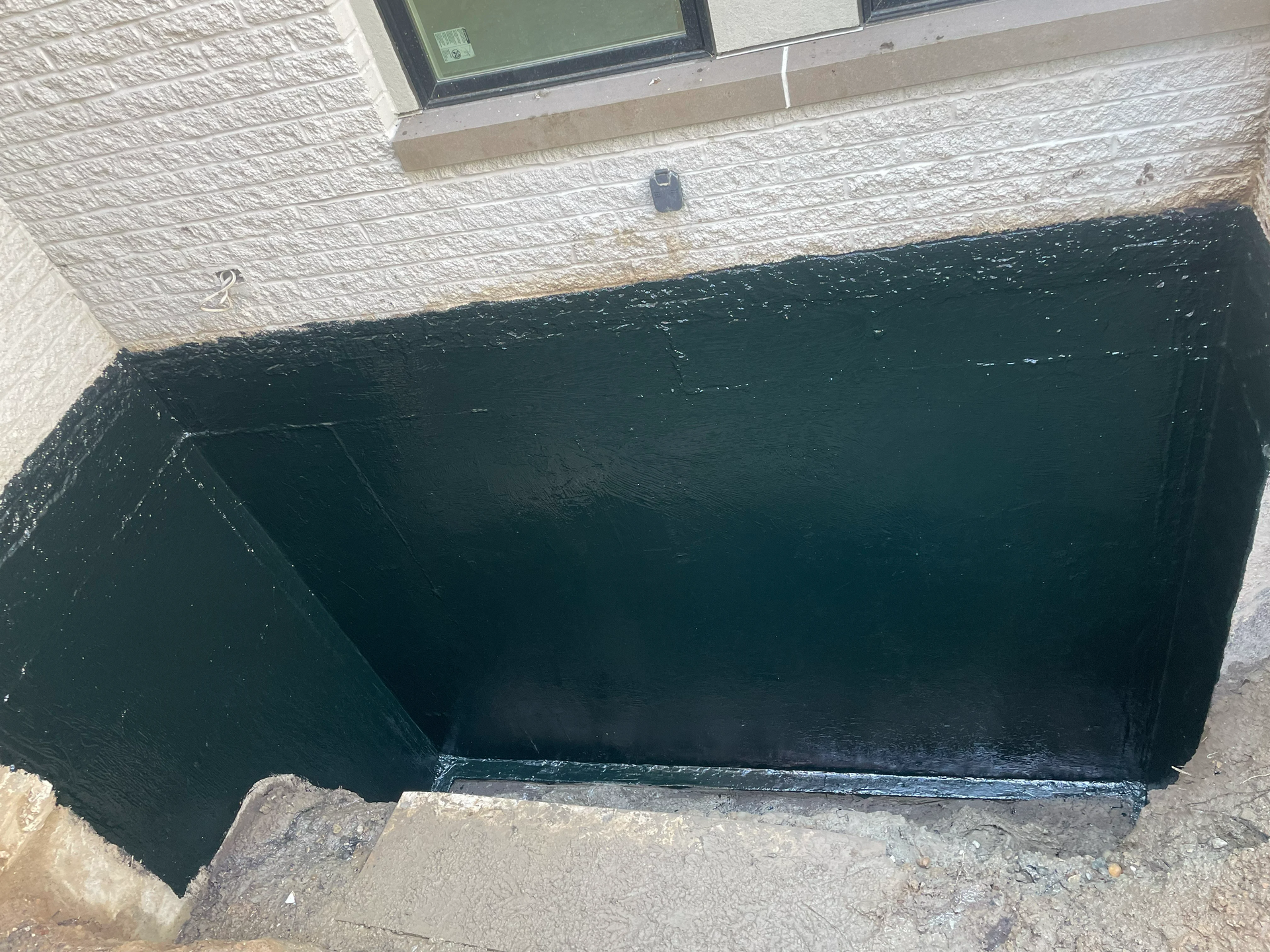 Freshly applied waterproof coating on a basement wall by EFD Masonry in Oakland County.
