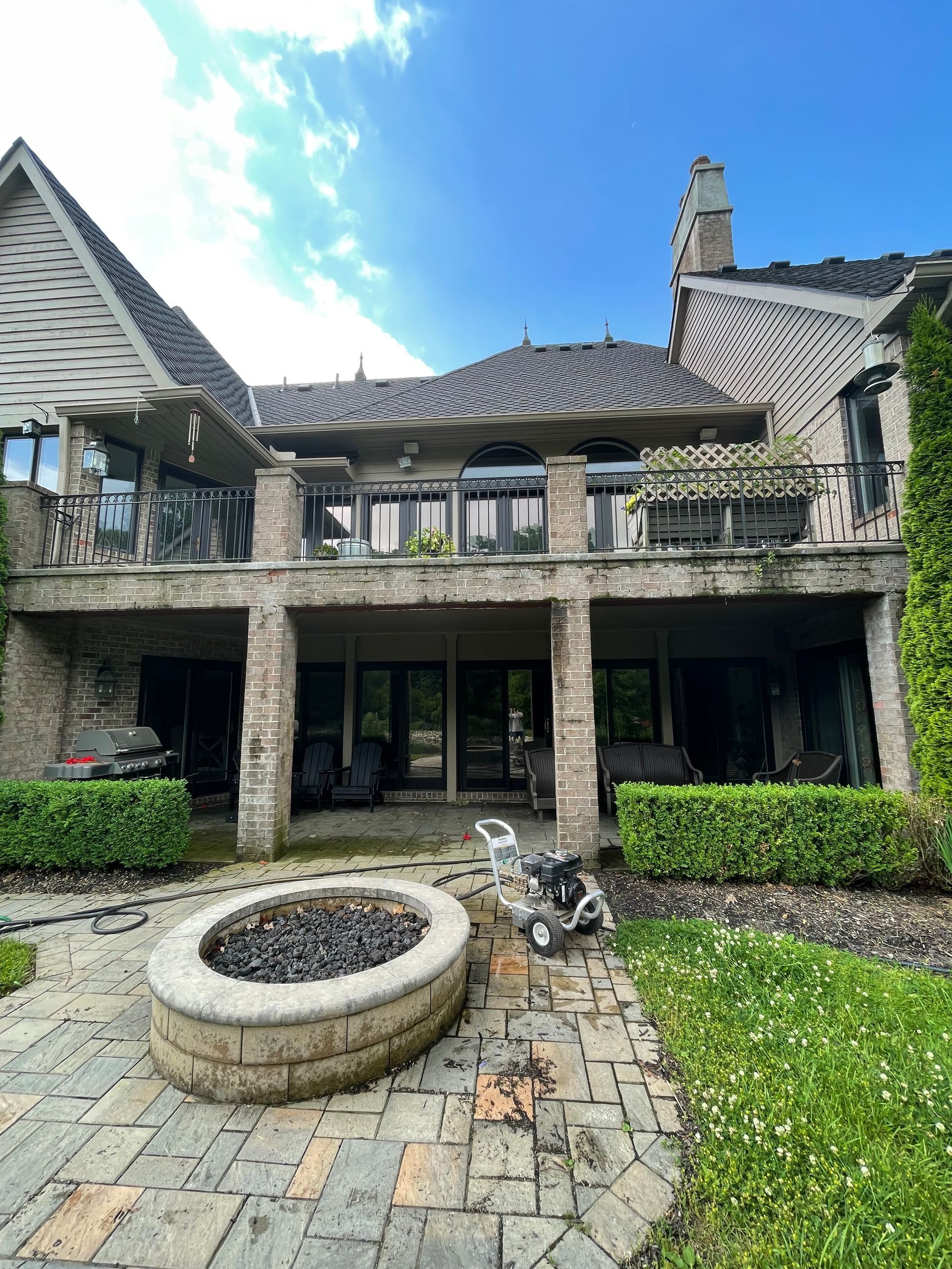 Stone courtyard with a circular fountain and ivy-covered two-story house under a bright blue sky