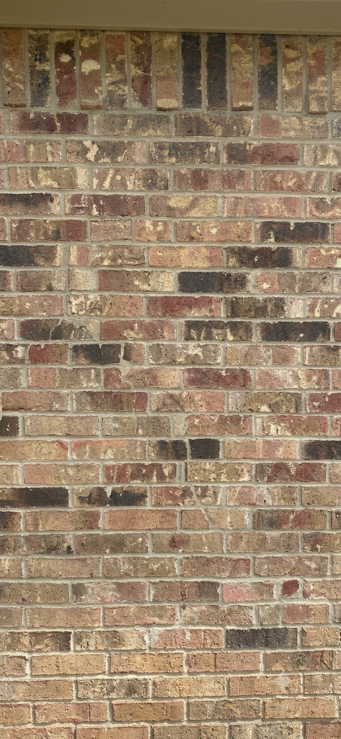 Brick wall with mottled red, tan, and gray bricks and white mortar lines