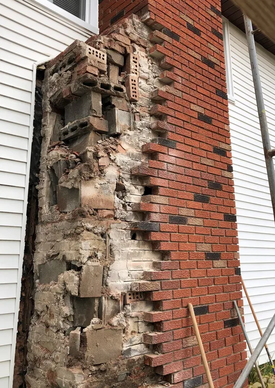 Partially demolished brick chimney revealing cinder blocks during EFD Masonry’s restoration process in Oakland County.