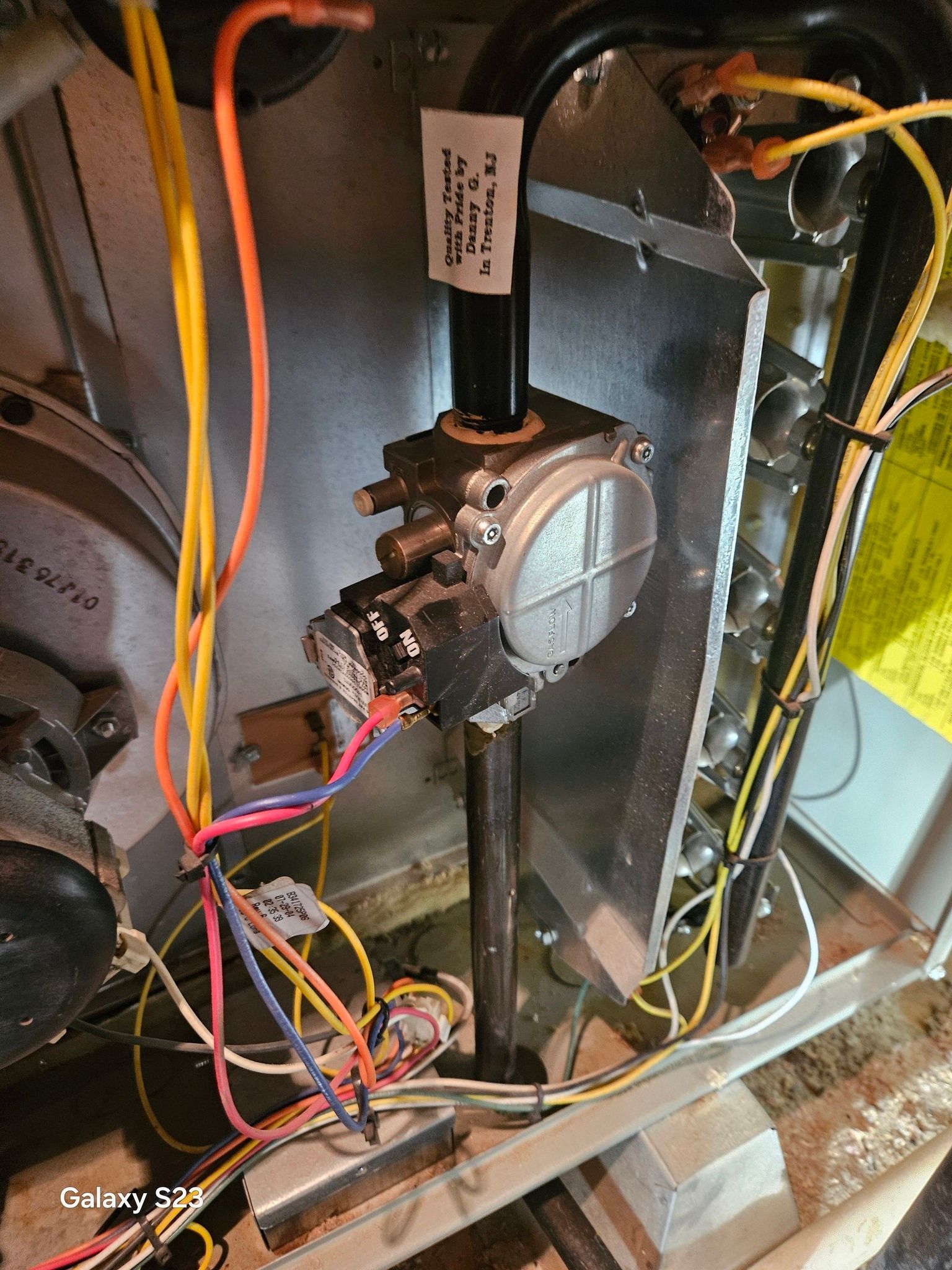 Gas furnace interior showing the gas valve, metal piping, and various electrical wires.