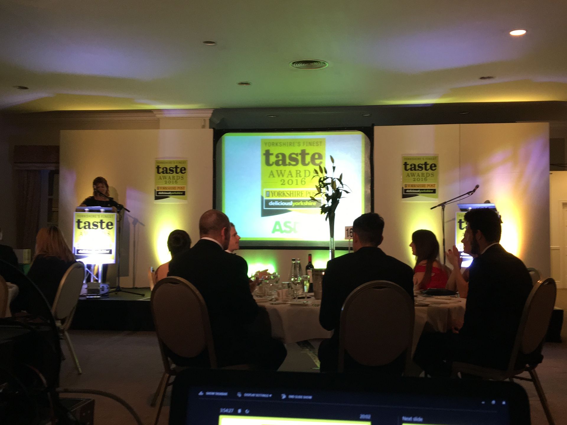 Projection screens, live cameras and uplighting on stage  at the front of a corporate event.Production services and equipment  for this business event was supplied by Exclusive Entertainments Harrogate,Yorkshire