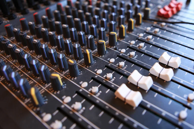 A close up of a mixer with many knobs and sliders