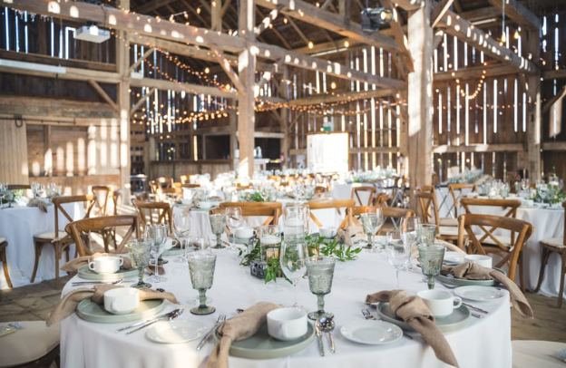 A barn filled with tables and chairs set up for a wedding reception.
