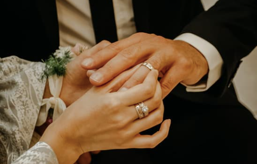 A man is putting a wedding ring on a woman 's finger.