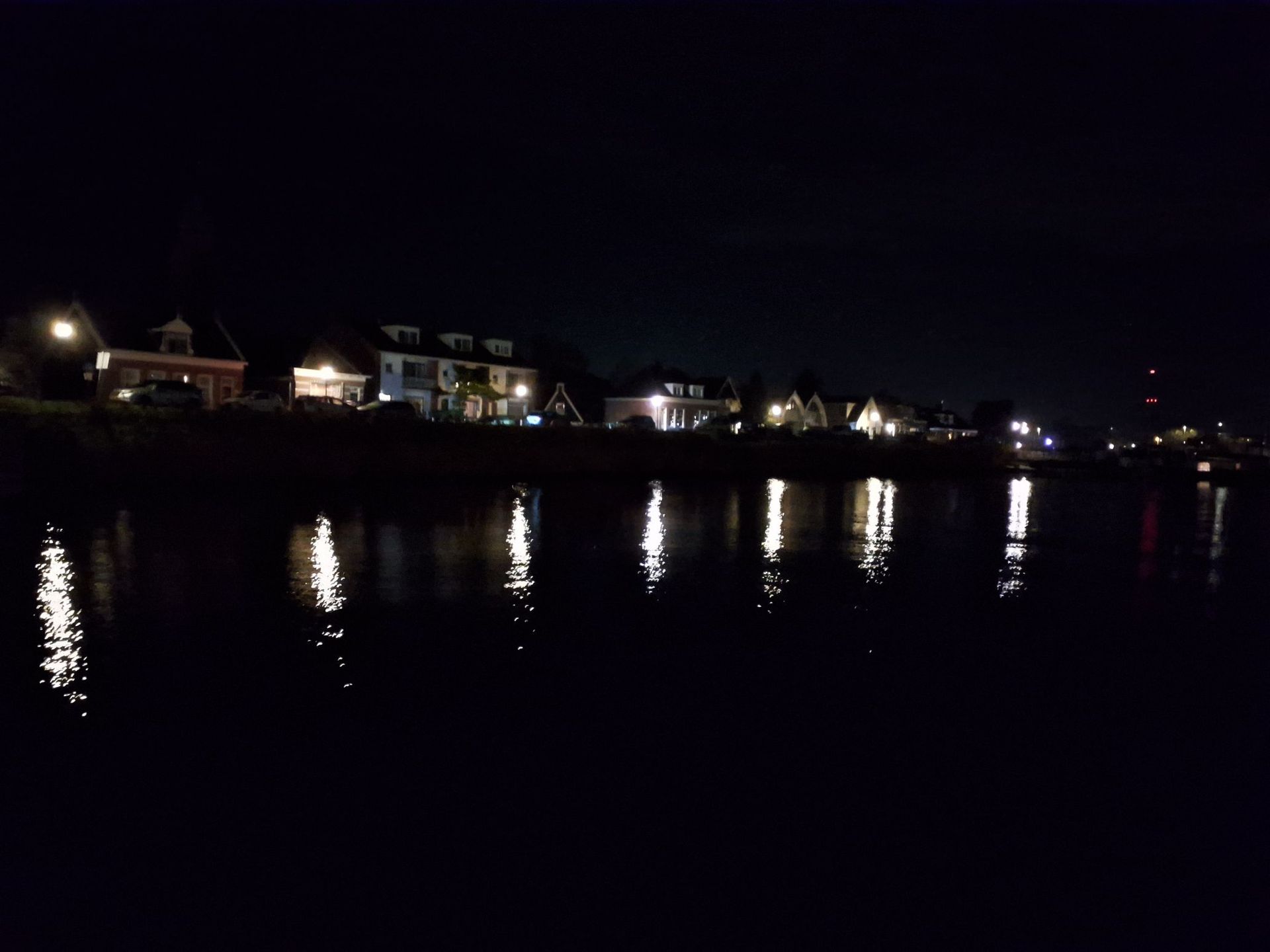 's Nachts de waterkant met verlichte gebouwen en hun weerspiegeling in het donkere water.