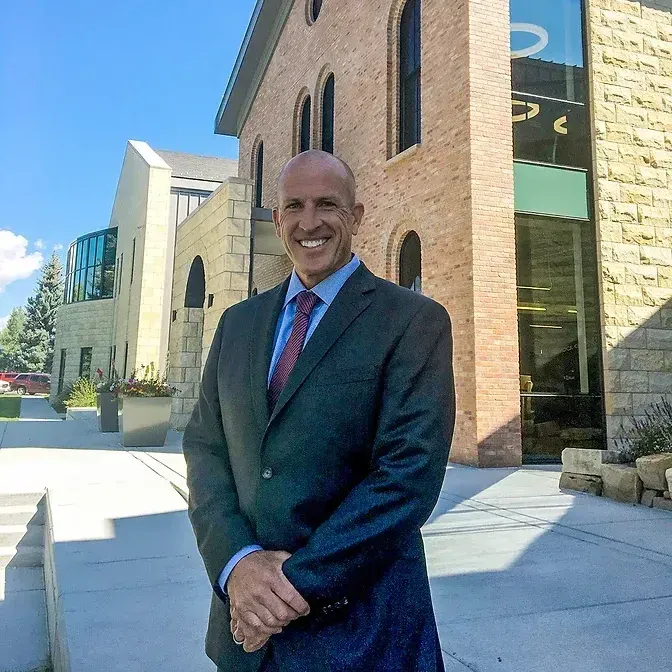 A man in a suit and tie is standing in front of a brick building