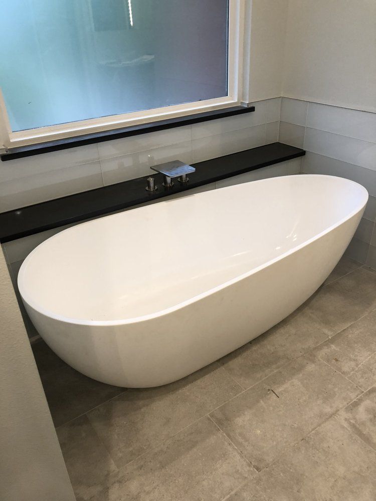 A white bathtub is sitting in a bathroom next to a window.
