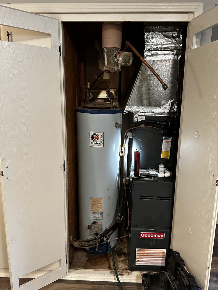 A water heater is sitting inside of a closet next to an air conditioner.