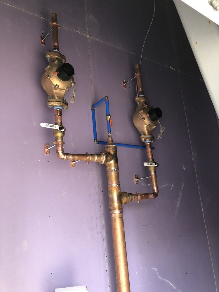 Two copper pipes are attached to a purple wall