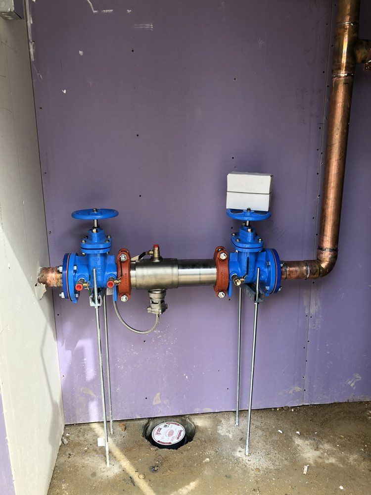 Two blue valves are connected to a copper pipe in a room.
