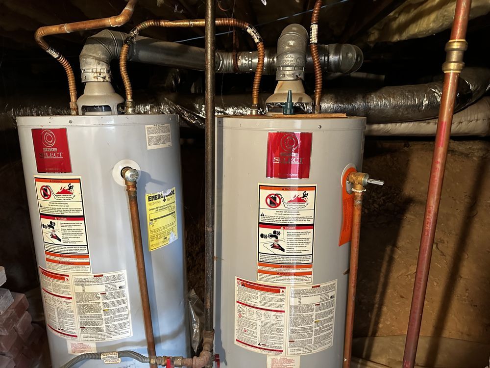 Two water heaters are sitting next to each other in a basement.