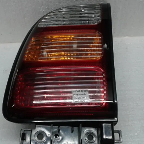 Primer plano de un conjunto de luces traseras de un coche negro con lentes rojas, ámbar y transparentes.