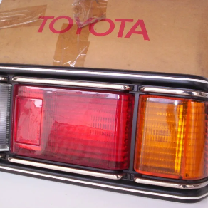 Luz trasera Toyota con detalles en rojo, ámbar y cromo sobre una carrocería color canela.