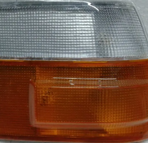 Primer plano de la luz de posición delantera de un coche con secciones superior transparente e inferior ámbar.