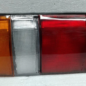 Primer plano del conjunto de luces traseras de un automóvil con secciones ámbar, blanca y roja.
