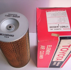 Filtro de aire Denso de Toyota junto a una caja roja de Toyota sobre una superficie blanca.