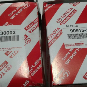 Cajas rojas de repuestos originales Toyota, una de ellas etiquetada como filtro de aceite, apiladas una al lado de la otra.