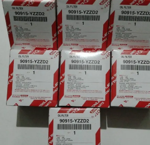 Cajas de productos blancas y rojas apiladas con la etiqueta 90915-YZZD2 en un estante.