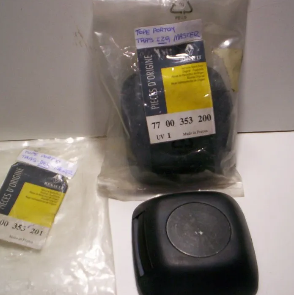 Piezas de plástico para automóviles en un embalaje transparente junto a un emblema cuadrado negro para automóvil y una etiqueta blanca.