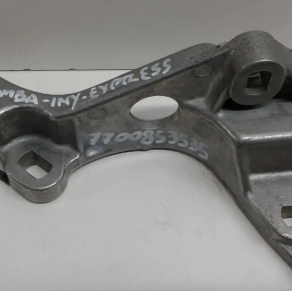 Soporte metálico para automóvil con marcas blancas escritas a mano y orificios para pernos sobre una superficie gris.