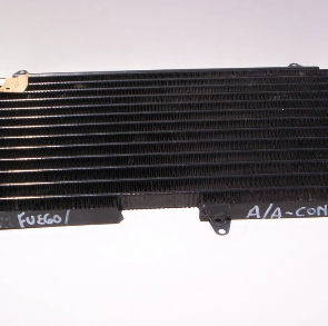 Radiador/condensador de aire acondicionado de coche negro sobre fondo blanco, con etiquetas escritas a mano en el borde inferior.