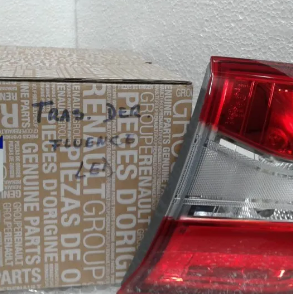 Una caja de cartón encajada junto a la luz trasera de un coche rojo contra una pared de hormigón.