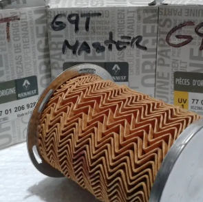 Filtro o recipiente cilíndrico de color óxido con un patrón en zigzag sobre un fondo de caja de cartón, etiquetado como “69T Master”.